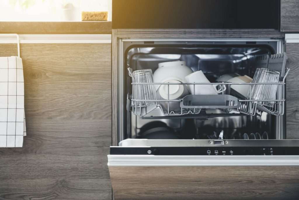 Close up of opened automatic stainless built-in dishwasher machine inside modern home kitchen with clean utensil. Household, housekeeping domestic life. Opening and closing washing machine